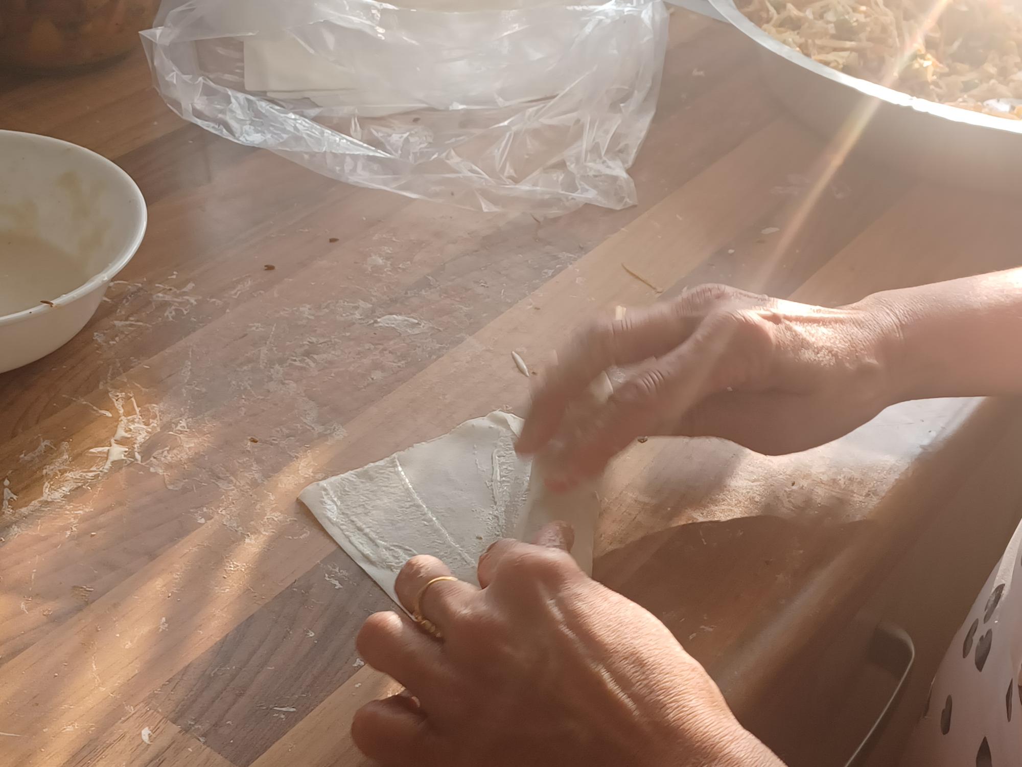 a pair of hands rolling a samosa