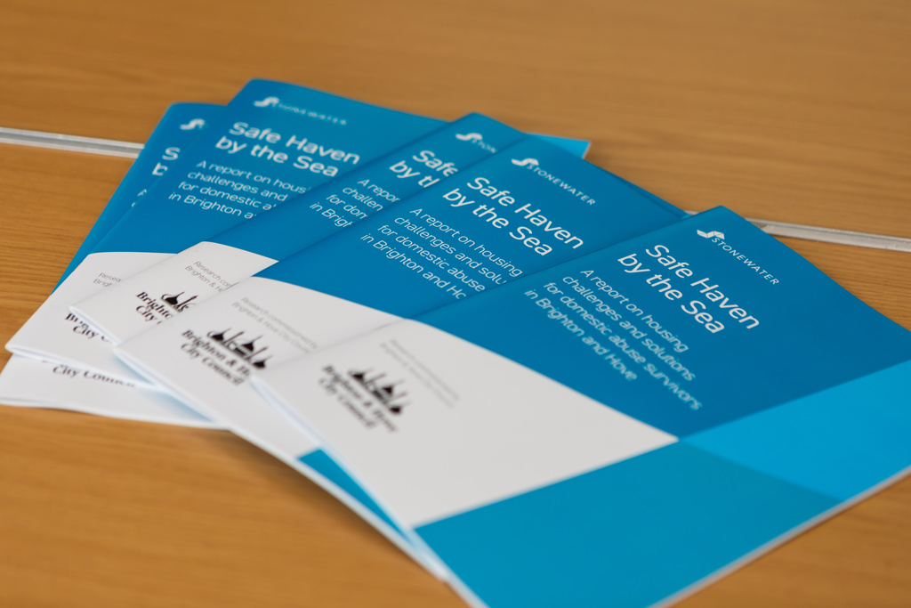 A fanned spread of paper copy Safe Haven by the sea reports on a wooden desk