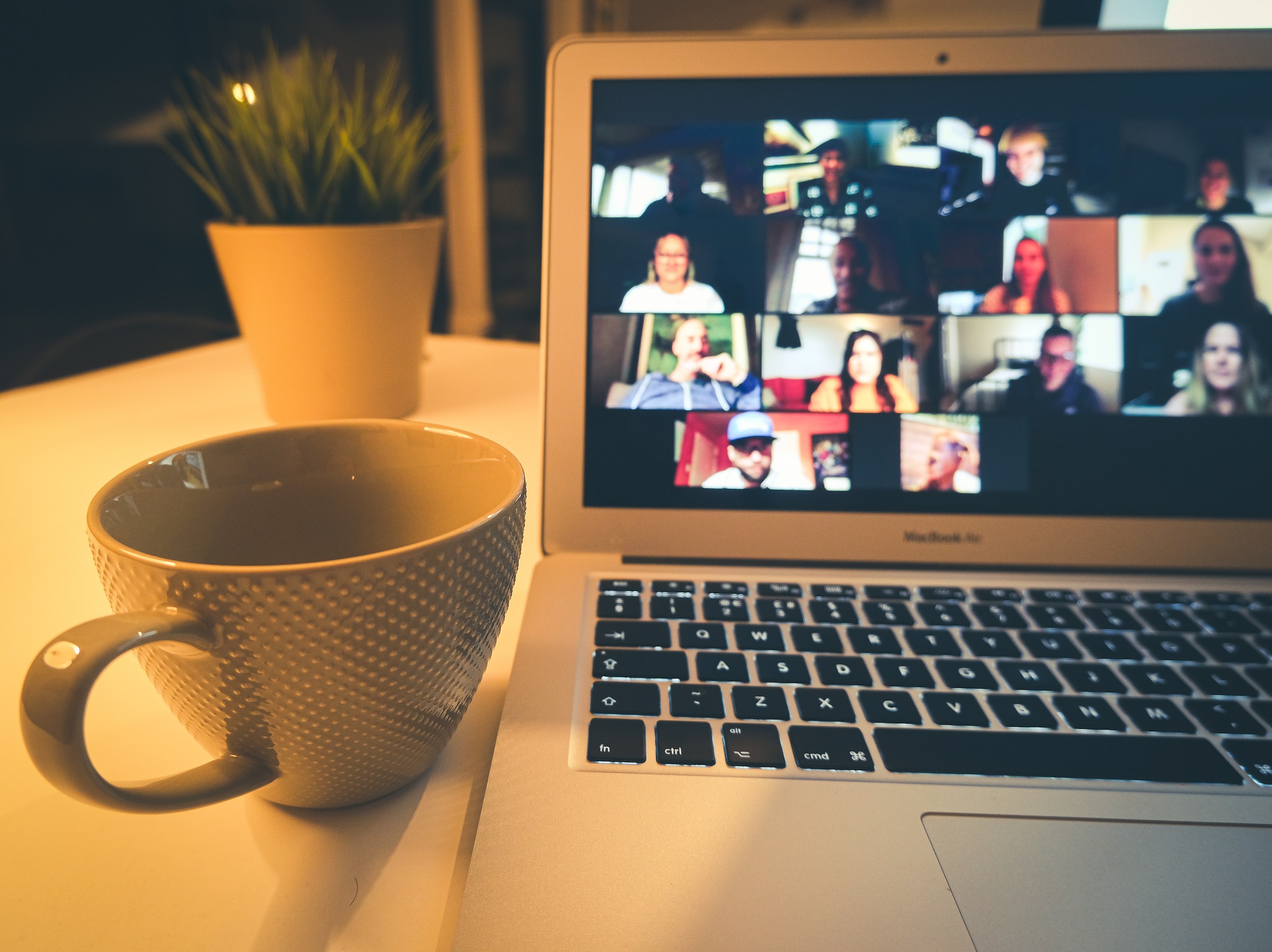 Close-up of mug of tea next to laptop screen showing 12 people on a video call