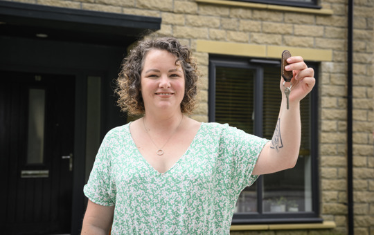 Customer living in our 7000th new home holding up her house keys and smiling